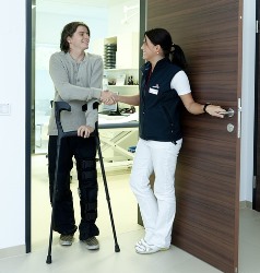 Arizona licensed practical nurse assisting patient with crutches at entrance